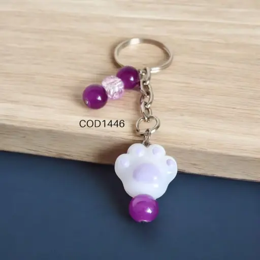 Llavero de patita de perro con perlas moradas.