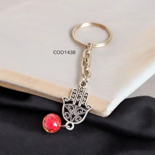 Llavero de mano con perla roja.